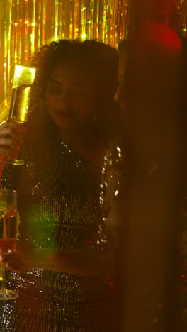 Vertikales-Video-Von-Zwei-Frauen-In-Einem-Nachtclub-Oder-Einer-Bar,-Die-Tanzen-Und-Alkohol-Trinken,-Mit-Funkelnden-Lichtern-Im-Hintergrund-2